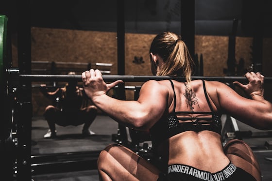 Person performing a weighted squat in a gym